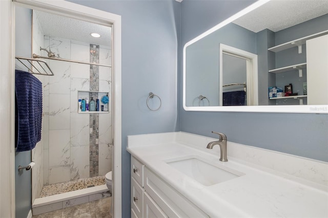 bathroom featuring a marble finish shower, toilet, a textured ceiling, and vanity