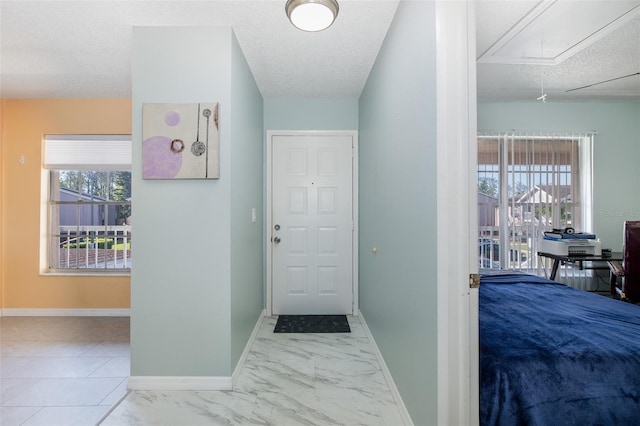 foyer featuring a wealth of natural light, baseboards, a textured ceiling, and marble finish floor