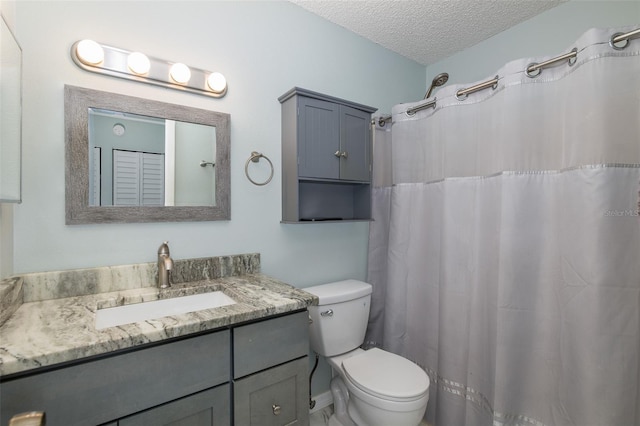 full bathroom featuring toilet, curtained shower, a textured ceiling, and vanity