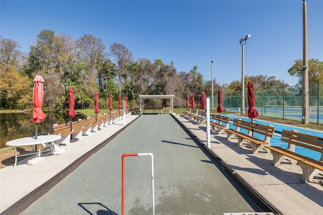 view of property's community with a tennis court and fence