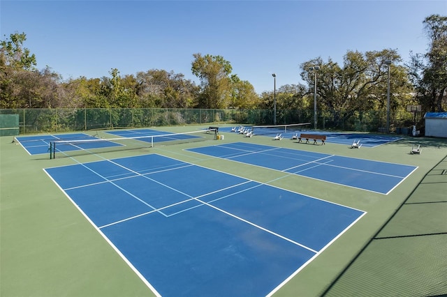 view of tennis court with community basketball court and fence