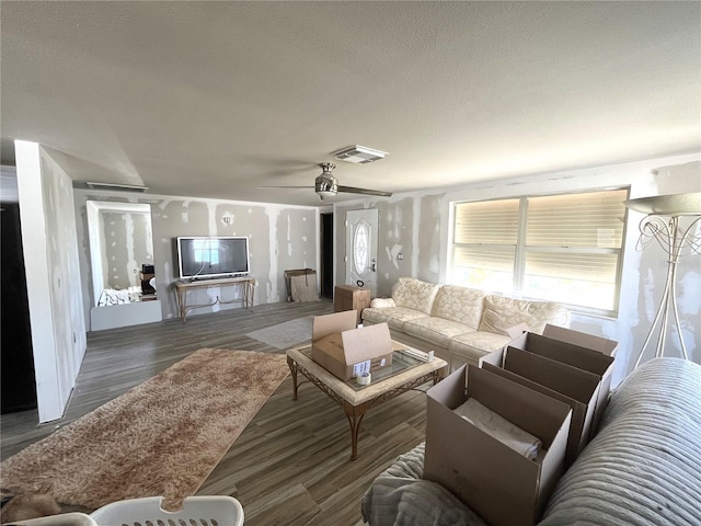 living area featuring ceiling fan, visible vents, a textured ceiling, and wood finished floors