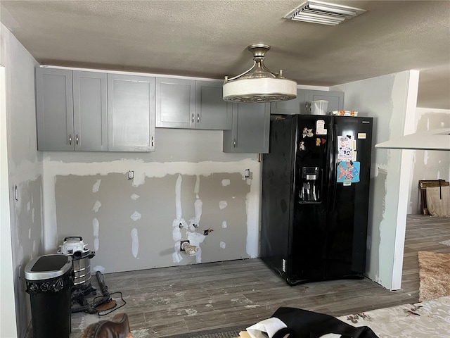 kitchen with wood finished floors, visible vents, gray cabinets, and black fridge