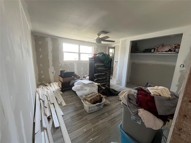 bedroom with a ceiling fan, wood finished floors, visible vents, and a textured ceiling