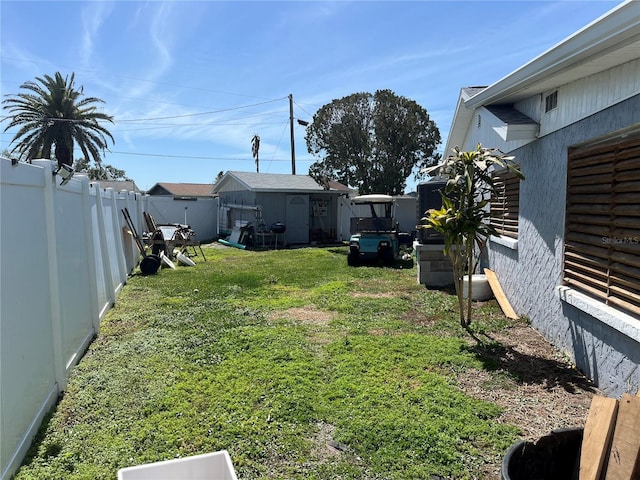 view of yard featuring a storage shed, an outbuilding, and a fenced backyard