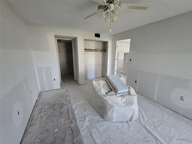 unfurnished bedroom with visible vents, a textured ceiling, and ceiling fan