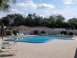 pool with a patio area and fence