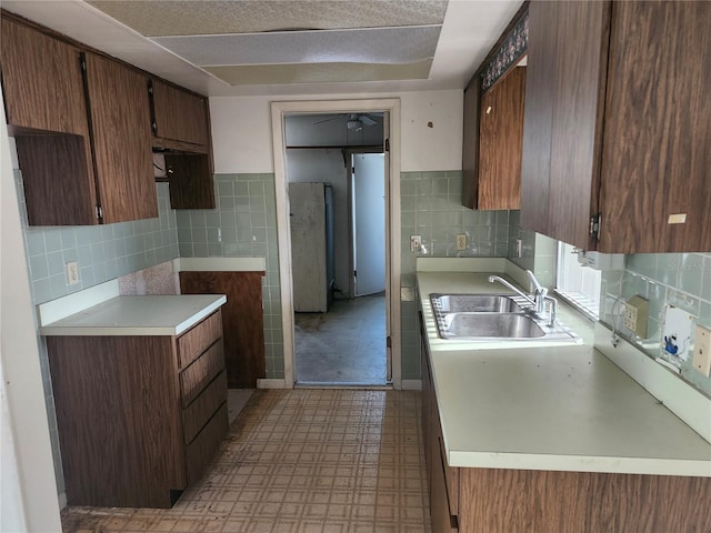 kitchen featuring backsplash, light floors, light countertops, and a sink