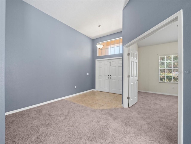 carpeted foyer entrance featuring baseboards and tile patterned flooring