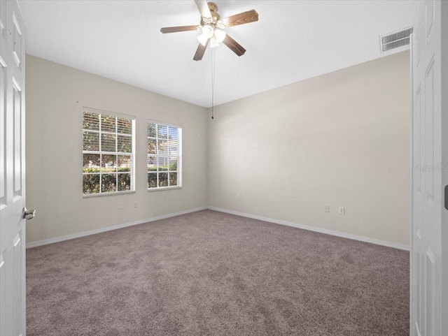 carpeted spare room featuring visible vents, baseboards, and ceiling fan