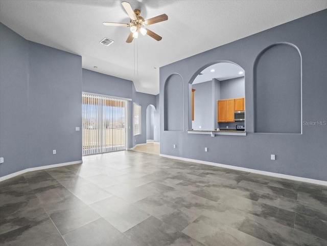 unfurnished living room with visible vents, arched walkways, baseboards, and a ceiling fan