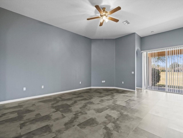 spare room with baseboards, arched walkways, visible vents, and ceiling fan