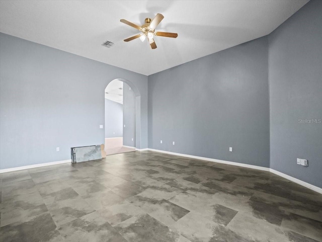 empty room featuring arched walkways, visible vents, baseboards, and ceiling fan