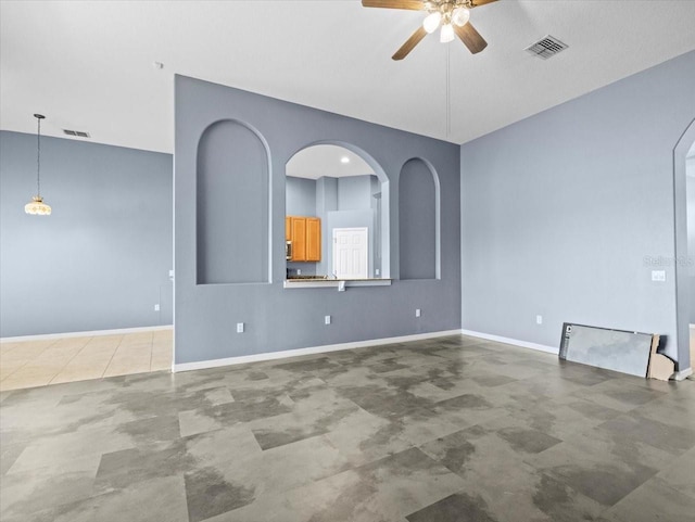 unfurnished room with visible vents, baseboards, arched walkways, and a ceiling fan