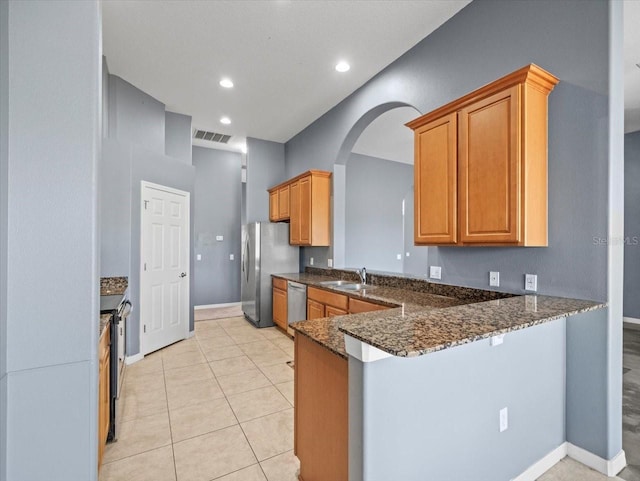 kitchen with visible vents, dark stone countertops, stainless steel appliances, a peninsula, and light tile patterned floors