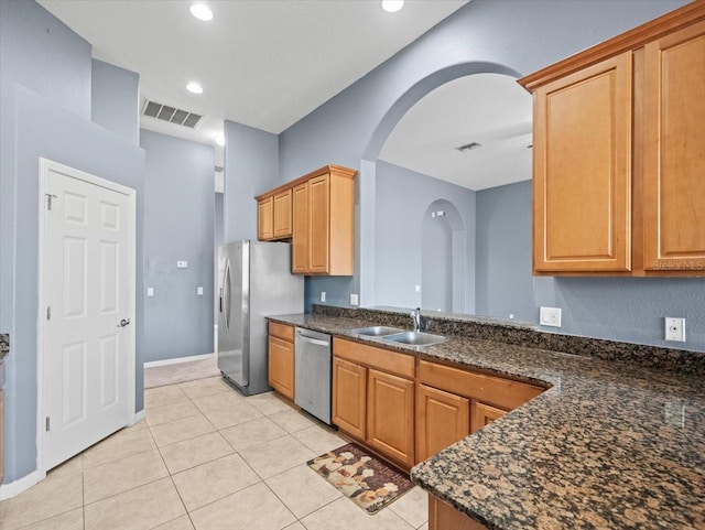 kitchen with a sink, stainless steel appliances, arched walkways, and visible vents