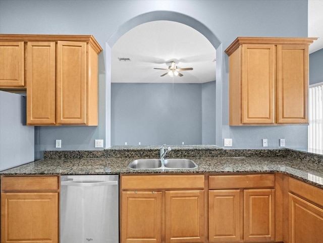 kitchen featuring a sink, dark stone countertops, stainless steel dishwasher, freestanding refrigerator, and ceiling fan