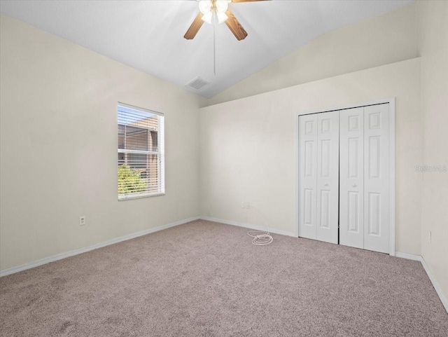 unfurnished bedroom with visible vents, a closet, carpet floors, ceiling fan, and vaulted ceiling