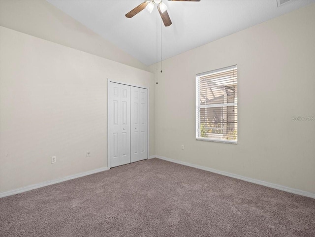 unfurnished bedroom featuring a ceiling fan, baseboards, lofted ceiling, a closet, and carpet flooring