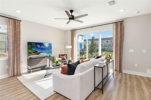 living area featuring visible vents, baseboards, a ceiling fan, and wood finished floors