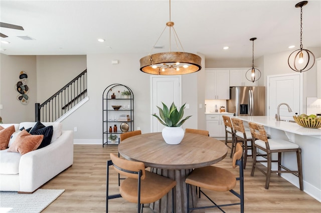 dining room with stairs, recessed lighting, light wood-style floors, and baseboards