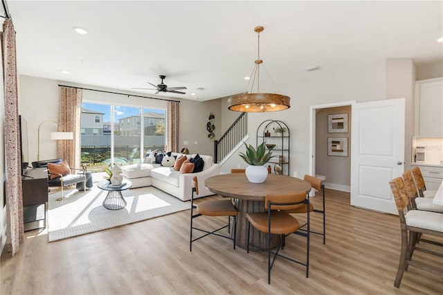 dining room featuring stairway, a ceiling fan, light wood finished floors, recessed lighting, and a view of city