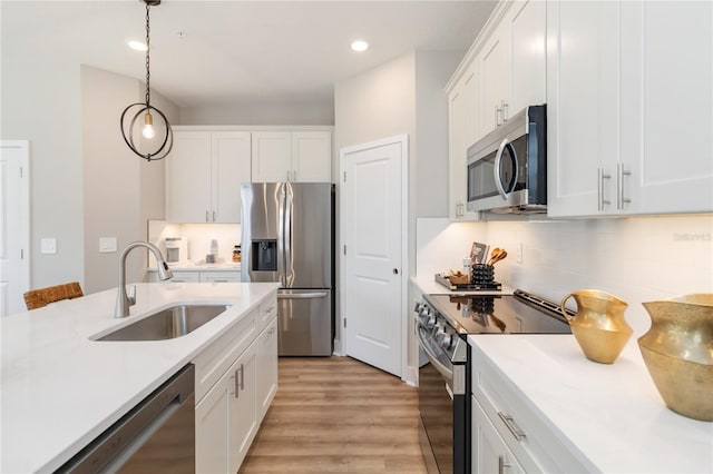 kitchen with white cabinets, stainless steel appliances, light countertops, and a sink