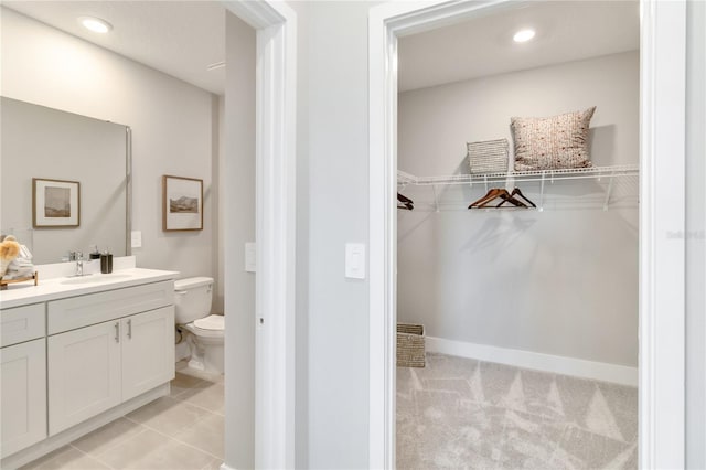 bathroom with vanity, a spacious closet, toilet, and recessed lighting