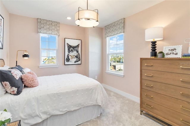 bedroom with light carpet, multiple windows, and baseboards