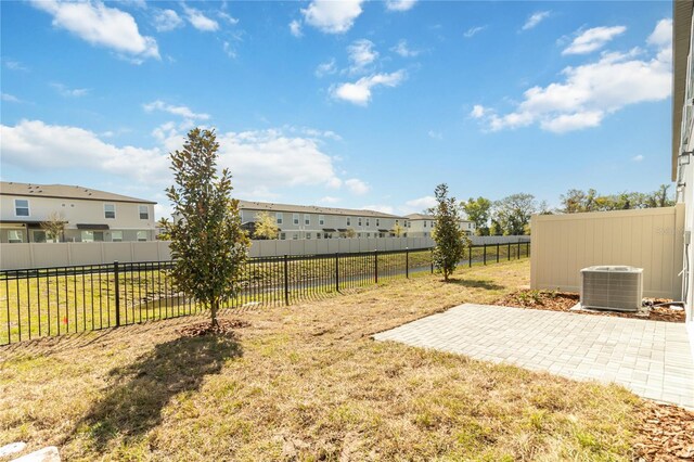 view of yard featuring a residential view, central AC, a fenced backyard, and a patio area