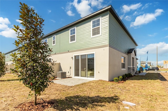 rear view of property featuring a patio, a yard, central AC unit, and stucco siding