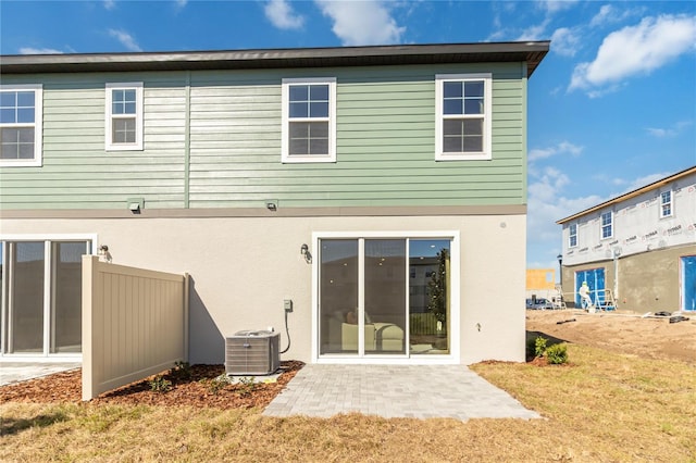 rear view of property with a patio, a yard, central AC unit, and stucco siding