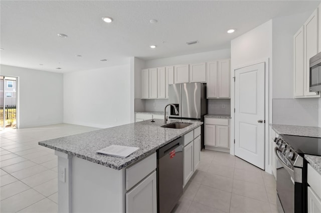 kitchen featuring light tile patterned floors, light stone countertops, a sink, decorative backsplash, and stainless steel appliances