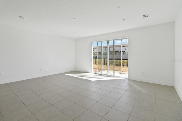 spare room featuring light tile patterned floors, visible vents, and baseboards