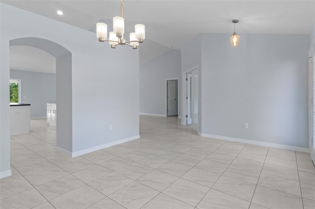 unfurnished room featuring arched walkways, a notable chandelier, and baseboards