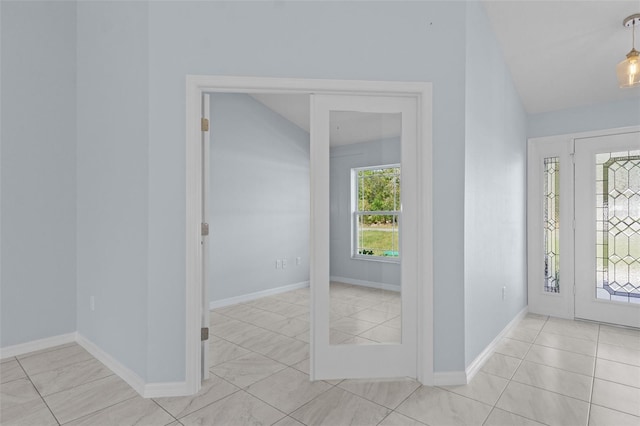 foyer featuring tile patterned floors, baseboards, and vaulted ceiling