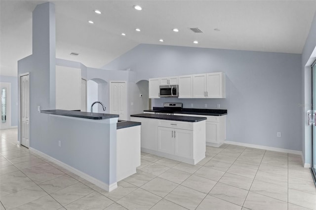 kitchen with visible vents, arched walkways, stainless steel appliances, white cabinets, and dark countertops