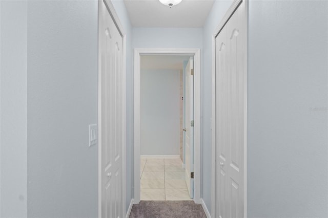 hallway featuring baseboards and light carpet