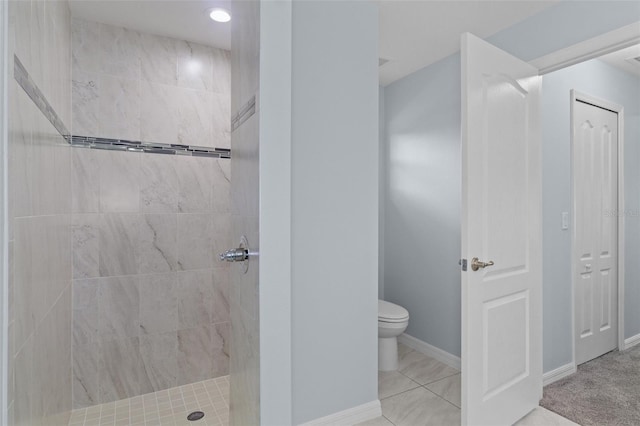 bathroom featuring toilet, baseboards, and a tile shower