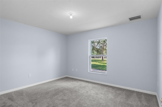 carpeted spare room with visible vents and baseboards