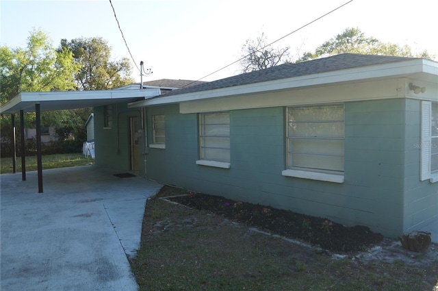 view of side of home featuring a carport, concrete block siding, and driveway