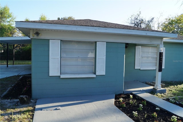 exterior space featuring roof with shingles and concrete block siding