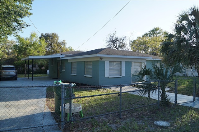 view of front of property with an attached carport, concrete driveway, a fenced front yard, and roof with shingles