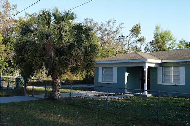 view of front facade featuring a fenced front yard, a shingled roof, and a front yard