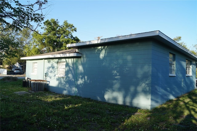 view of side of home with a lawn and cooling unit