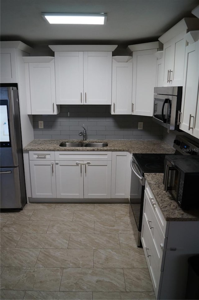 kitchen featuring a sink, white cabinetry, electric range oven, and freestanding refrigerator