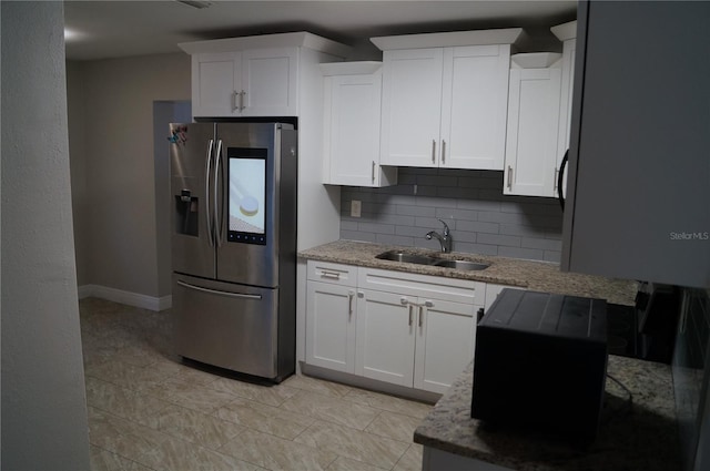 kitchen featuring backsplash, white cabinets, stainless steel refrigerator with ice dispenser, and a sink