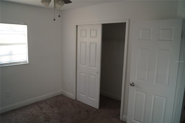 unfurnished bedroom featuring baseboards, dark colored carpet, and a closet