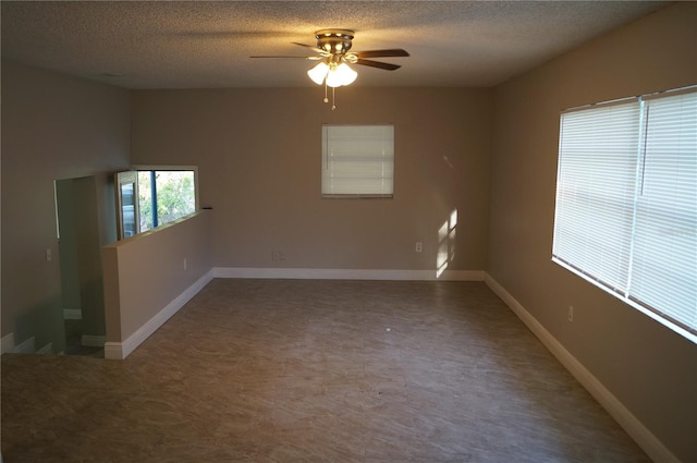 unfurnished room with ceiling fan, a textured ceiling, and baseboards