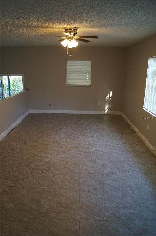 spare room featuring a ceiling fan, baseboards, and a textured ceiling